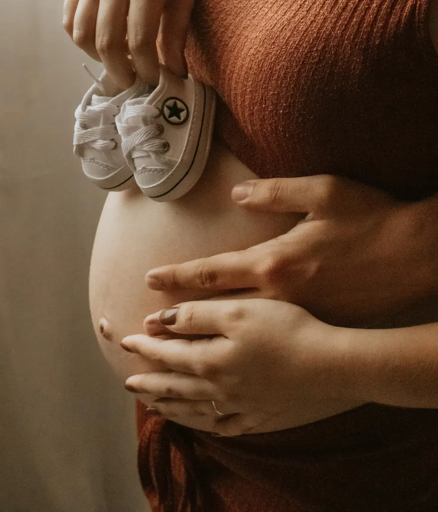 Expecting parents holding baby shoes against the bump